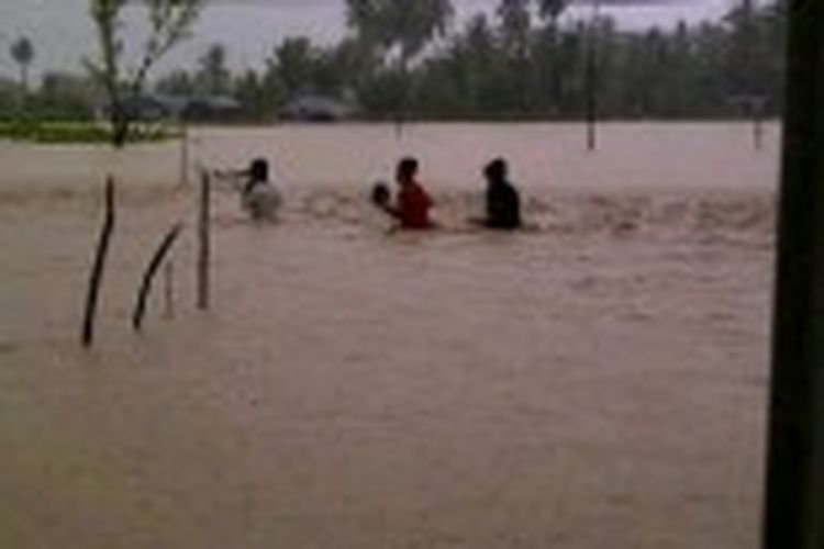Warga salah satu desa di Kecamatan Malaka Barat, Kabupaten Malaka, Nusa Tenggara Timur, Minggu (23/6/2013), berusaha melewati banjir yang melanda desa mereka.
