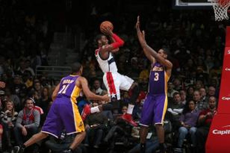 Pebasket Wahington Wizards, John Wall (putih) melewati pemain Los Angeles Lakers untuk memasukkan bola. Wizards dan Lakers bertemu pada lanjutan kompetisi NBA, di Verizon Center, Selasa (26/11/2013).