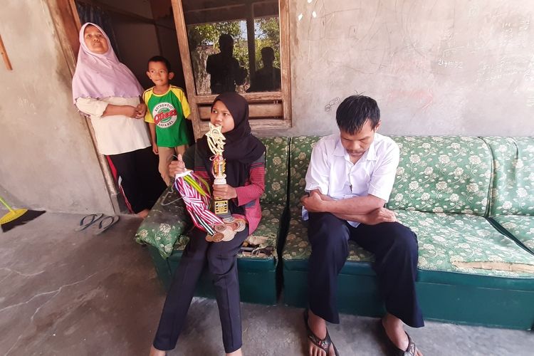 Ishma Tukha Nur Solechah (13) Memegang Piagam diapit Orang tuanya pasangan Slamet Supriyano dan Turisah di Rumahnya Kapanewon Playen Gunungkidul Minggu (23/8/2020)