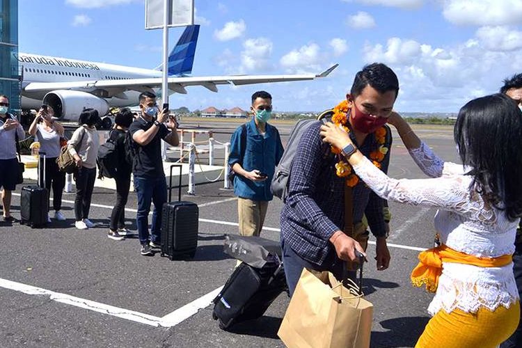 Petugas mengalungkan bunga untuk menyambut penumpang pesawat rute domestik yang tiba di Bandara Internasional I Gusti Ngurah Rai, Badung, Bali, Jumat (31/7/2020). Pemerintah Provinsi Bali mulai membuka sektor pariwisata bagi wisatawan domestik pada Jumat (31/7) dengan sejumlah persyaratan yang mengedepankan aspek kesehatan dan kualitas untuk memberi pelindungan, kenyamanan dan keamanan bagi wisatawan yang berkunjung selama masa pandemi Covid-19.