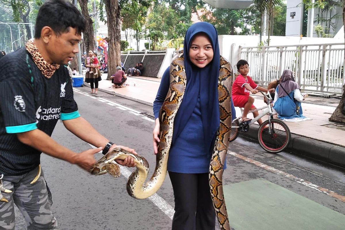 Miki dan Laksmi saat melakukan peragaan ular di Car Free Day (CFD) Jalan Raya Darmo Surabaya, Minggu (1/6/2025).