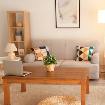 Ilustrasi ruang tamu dengan sofa abu-abu dan meja kayu