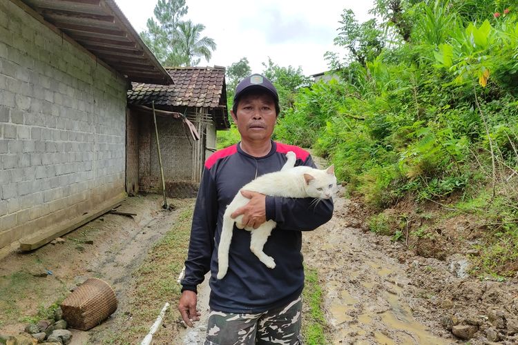 Seorang warga terdampak tanah gerak dan longsor di Dusun Depok Desa Ngrandu Kecamatan Suruh Trenggalek Jawa Timur, menyelamatkan kucing kesayangannya, Kamis (19/12/2024).