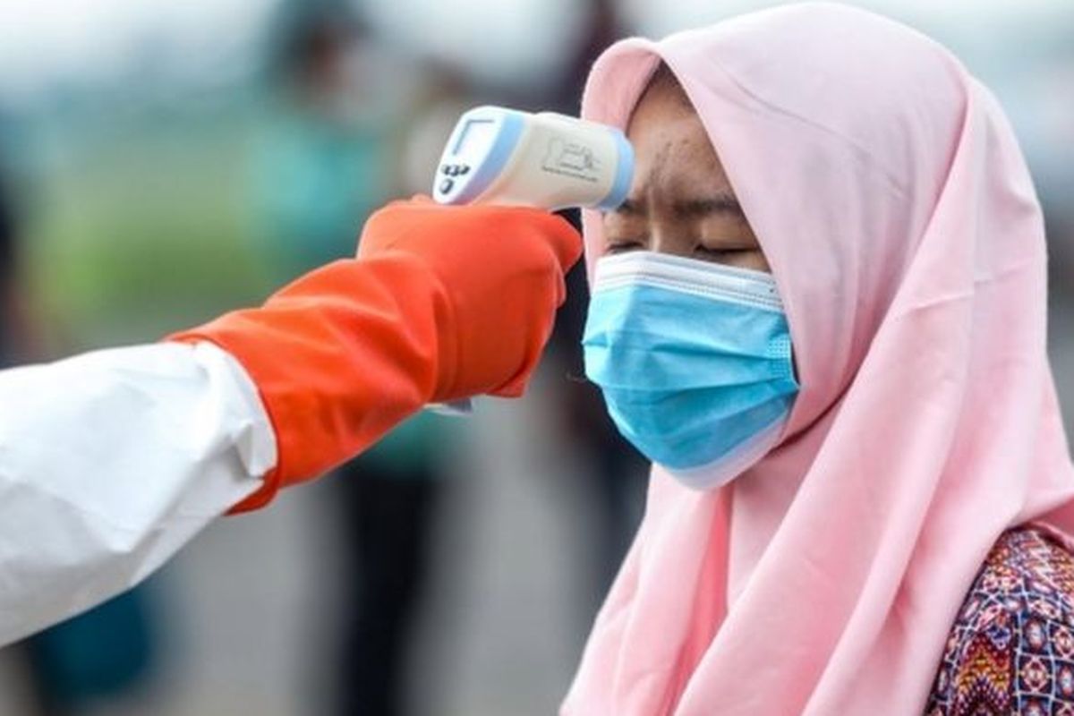 Seorang pekerja migran Indonesia diperiksa suhu tubuhnya saat tiba di Lanud Soewondo di Medan, Sumatera Utara, 10 April 2020 lalu.