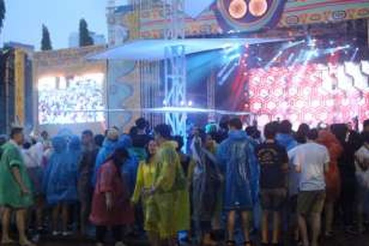 Para pengunjung We The Fest 2016 di Parkir Timur Senayan, Jakarta, mengenakan jas hujan saat menyaksikan aksi band Sheila On 7, Minggu (14/8/2016).