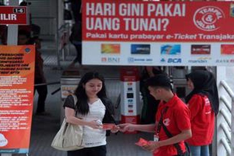 Petugas membagikan brosur E-Tiket Transjakarta kepada penumpang yang keluar dari Halte Bus Transjakarta Bendungan Hilir, Jakarta Pusat,  Kamis (22/1/2013). Selain untuk sosialisasi, kegiatan tersebut juga melayani pembelian e-tiket yang mulai diberlakukan di Koridor 1 Blok M-Kota.
