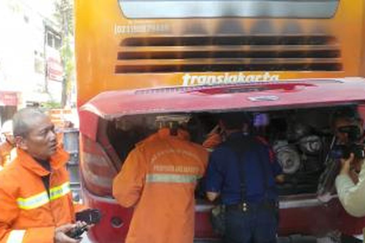 Beberapa petugas pemadam kebakaran mengecek bagian mesin bus transjakarta yang terbakar di Halte Stasiun Jatinegara 2. Dari mesin belakang bus ini diduga awal terjadinya kebakaran. Sabtu (18/7/2015).