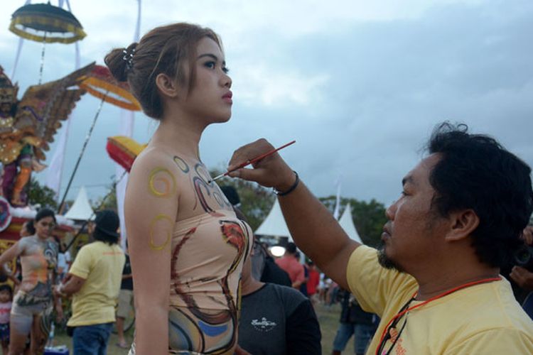 Seniman melukis tubuh model saat pagelaran Sanur Village Festival 2018 di Pantai Matahari Terbit Sanur, Bali, Sabtu (25/8/2018). Kegiatan bertema Mandala Giri tersebut menampilkan berbagai ide kreatif bidang seni tentang gunung berapi yang bertujuan untuk meningkatkan sektor pariwisata.