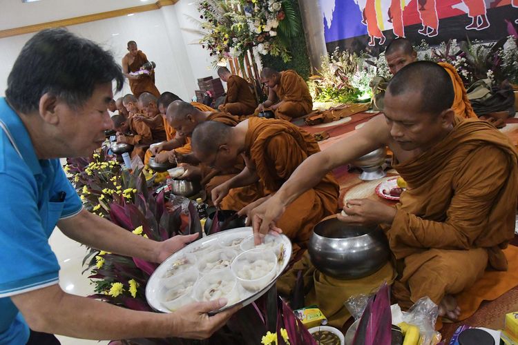 Umat Buddha (kiri) memberikan persembahan makanan kepada biksu yang mengikuti  perjalanan ritual keagamaan (thudong)  di Bekasi, Jawa Barat, Jumat (12/5/2023). Sebanyak 32 biksu dari sejumlah negara tersebut jalan kaki dari Thailand menuju Candi Borobudur  dalam rangka menyambut Hari Raya Waisak pada 4 Juni 2023.