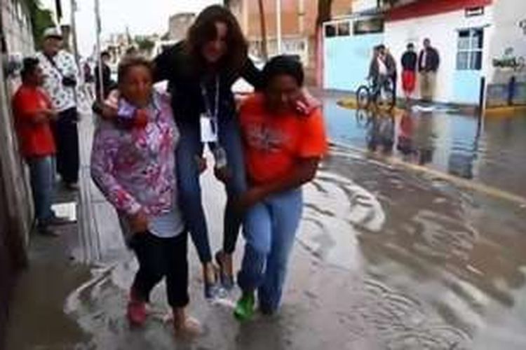 Jurnalis TV Azteca, Lydia Cumming digendong warga saat melintas di genangan air ketika meliput bencana banjir di Puebla, wilayah tengah Meksiko. Setelah foto ini tersebar di media sosial, Lydia dipecat dari pekerjaan.