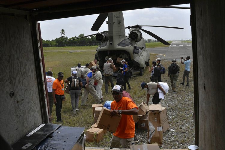 Orang-orang menurunkan bantuan kemanusiaan dari helikopter Angkatan Darat AS di bandara di Les Cayes, Haiti, Minggu, 22 Agustus 2021.