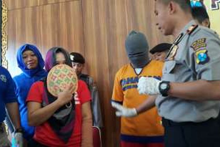 Linda Meiyana, tersangka ibu empat anak pengedar narkoba menutup muka dengan kipas saat digelar kasusnya di Mapolres Madiun, Selasa (25/10/2016)