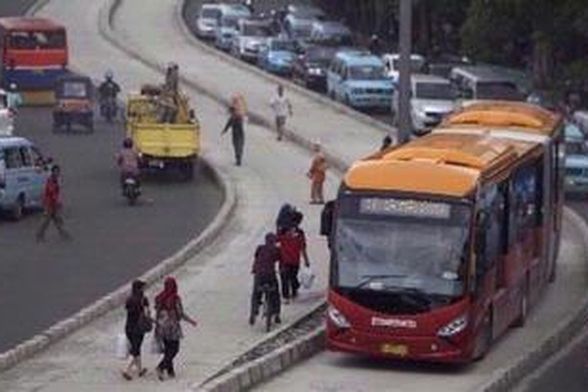 Warga lalu lalang di samping bus gandeng transjakarta di depan Stasiun Jatinegara di Jalan Bekasi Barat Raya, Jakarta Timur, Rabu (28/12/2011). Koridor XI bus transjakarta (Kampung Melayu-Pulogebang) secara resmi dioperasikan dengan total lintasan sepanjang 11,76 kilometer. Lima kilometer diantaranya merupakan jalur campuran, sehingga perlu lebih berhati-hati baik warga maupun pihak operatornya. KOMPAS/AGUS SUSANTO