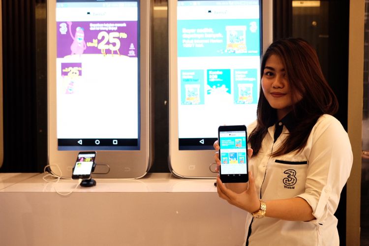 Model menunjukkan aplikasi Bima Plus buatan Tri di smartphone.
