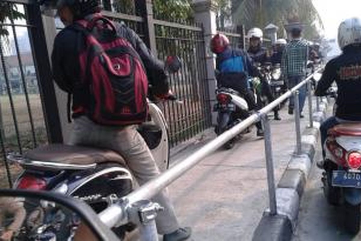 Seorang pejalan kaki terjepit di antara pengendara motor yang menggunakan trotoar untuk menghindari kemacetan.