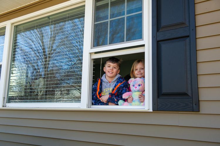 George dan Emma Killingworth, 7, dengan boneka teddy bear mereka, melihat keluar dari jendela rumah mereka di Haverhill, Massachusetts, AS 27 Maret 2020. Tetap di rumah aja untuk mencegah penyebaran virus corona. EPA-EFE/AMANDA SABGA