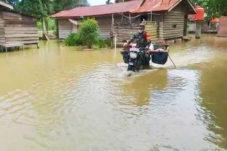 Babinsa Koramil 10/Kunto Darussalam Kopda Jantri Istani terobos banjir hampir semeter saat menyalurkan bantuan sembako kepada para korban banjir di Desa Kasang Mungkal, Kecamatan Bonai Darussalam, Kabupaten Rohul, Riau, Rabu (31/3/2021).