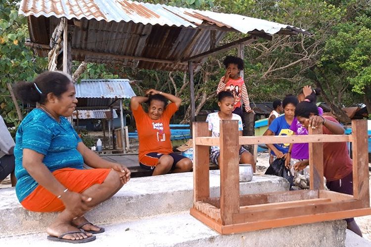 Warga Biak duduk di pinggir Pantai Bosnik, Papua Barat.