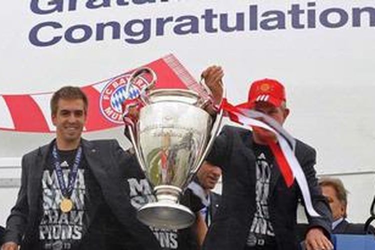 Kapten Bayern Muenchen Philipp Lahm dan pelatih kepala Jupp Heynckes (kana), mengangkat trofi Liga Champions saat tim tiba di bandara Muenchen, Minggu (26/5/2013). Bayern menjuarai Liga Champions setelah di final menang 2-1 atas Borussia Dortmund.