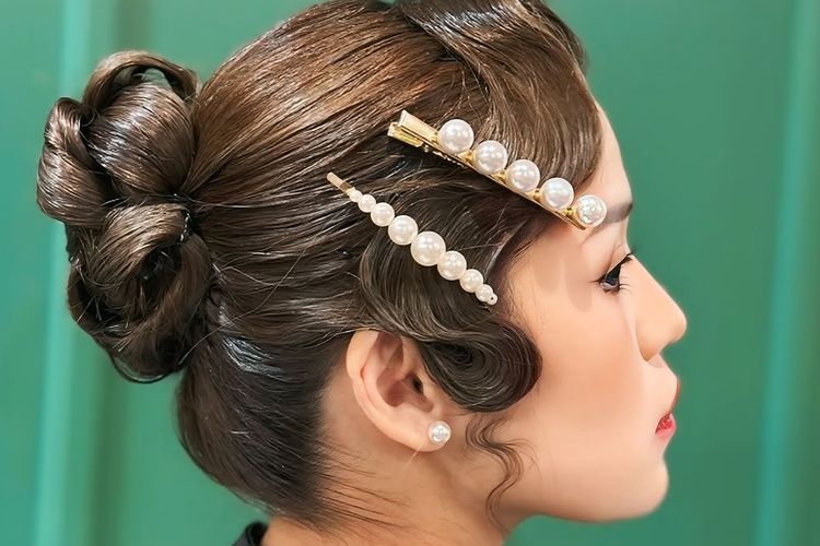 Model dengan tatanan rambut vintage roll bun.