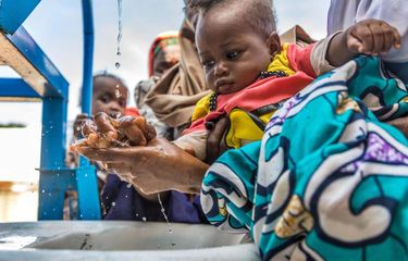 Seorang ibu mencuci tangan dan tangan anaknya sebelum anaknya menjalani tes nafsu makan sebagai bagian dari program pengobatan CMAN di Pusat Kesehatan di Bauchi, Nigeria.  Riset UNICEF dan WHO menemukan 3 dari 10 orang atau sekitar 2,3 miliar orang di dunia tidak memiliki fasilitas cuci tangan dengan air dan sabun di rumah.