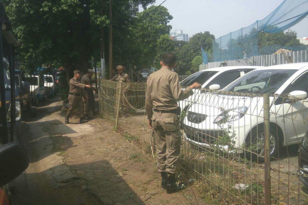 Satpol PP membongkar pagar yang membatasi trotoar dengan saluran air di depan showroom Honda Tebet, Kamis (31/8/2017).