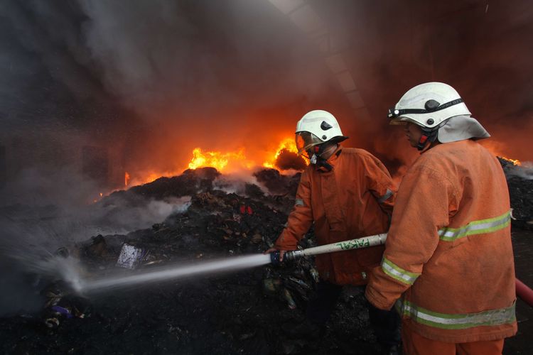 Petugas Dinas Pemadam Kebakaran Kota Surabaya memadamkan gudang yang terbakar di kawasan Pergudangan Margomulyo Permai, Surabaya, Jawa Timur, Selasa (12/4/2022). Sebanyak 25 kendaraan pemadam kebakaran dikerahkan untuk memadamkan api yang meludeskan satu gudang penyimpanan barang elektronik serta kabel dan satu gudang penyimpanan sandal serta sepatu itu.