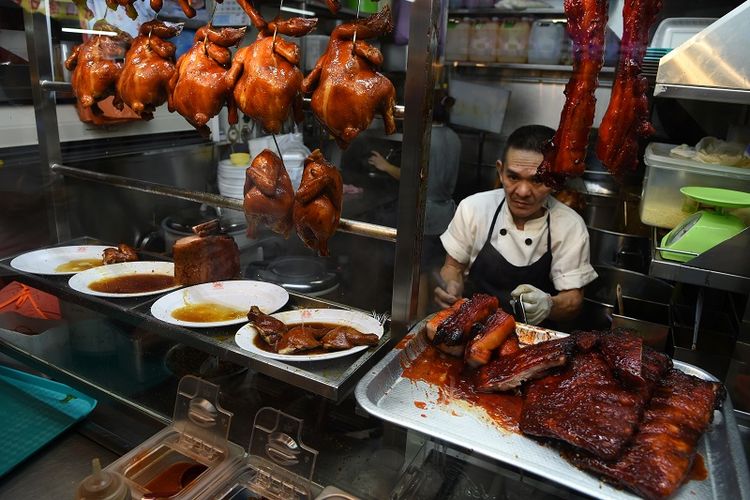 Dalam foto ini menunjukkan penjual makanan jalanan di Singapura Chan Hon Meng sedang menyiapkan pesanan pelanggannya. 