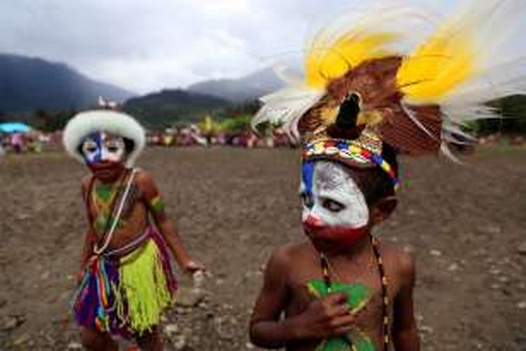 Anak kecil berpose saat menghadiri upacara adat bakar batu di Lapangan Trikora, Distrik Ilaga, Kabupaten Puncak, Papua, Kamis (15/9/2016). Tradisi bakar batu merupakan salah satu tradisi terpenting di Papua yang berfungsi sebagai tanda rasa syukur, menyambut tamu, atau acara perdamaian setelah perang antar suku.