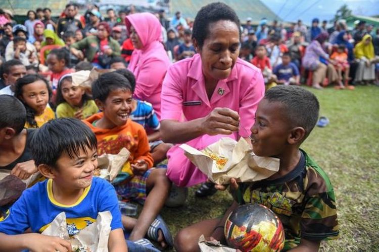 Dua orang Ibu Bhayangkari menyuapi makan pada bocah pengungsi di Posko pengungsian di Makodim 1702/Jayawijaya, Wamena, Papua, Selasa (8/10). 