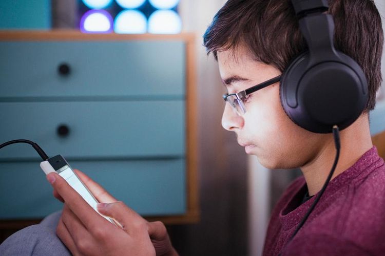 Ilustrasi: anak dan remaja gunakan headphone untuk mendengar musik dari smartphone.