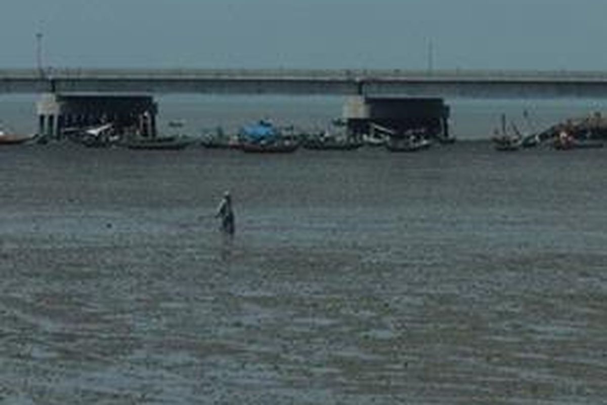 Seorang nelayan berdiri di depan jembatan Suramadu yang sedang dibangun.