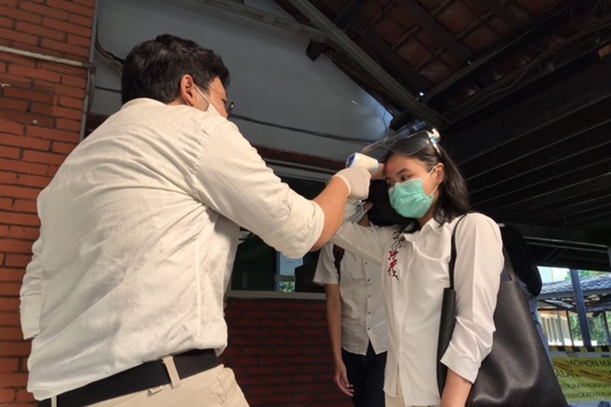 Panitia UTBK SBMPTN 2020 mengukur suhu peserta sebelum masuk ruang ujian di Fakultas Ilmu Pengetahuan Budaya Universitas Indonesia (FIB UI), Depok, Jawa Barat, Minggu (5/7/2020).