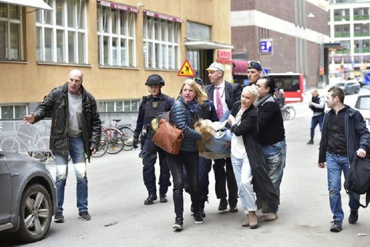 Para saksi mata menggotong seorang korban ke rumah sakit pasca-serangan truk di Stockholm, Swedia, Jumat (7/4/2017).