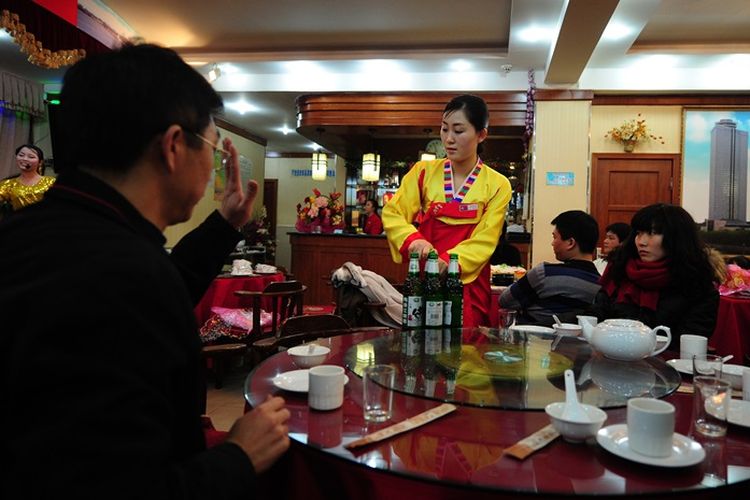 Pelayan restoran Korea Utara melayani pelanggan seperti yang dilakukan orang lain pada acara hiburan malam di restoran tersebut pada 26 November 2010, di Dandong, provinsi Liaoning, China . (AFP/Frederic J Brown)

