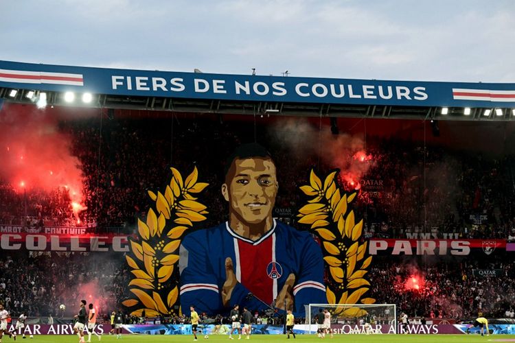 Para pendukung bersorak di belakang tifo raksasa yang menggambarkan penyerang Paris Saint-Germain asal Perancis Kylian Mbappe sebelum pertandingan sepak bola Ligue 1 Prancis antara Paris Saint-Germain (PSG) dan Toulouse (TFC) pada 12 Mei 2024 di stadion Parc des Princes, Paris. (Photo by MIGUEL MEDINA / AFP)