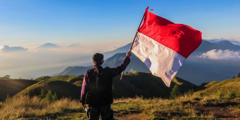 Seorang pendaki mengibarkan bendera merah putih di Gunung Prau.