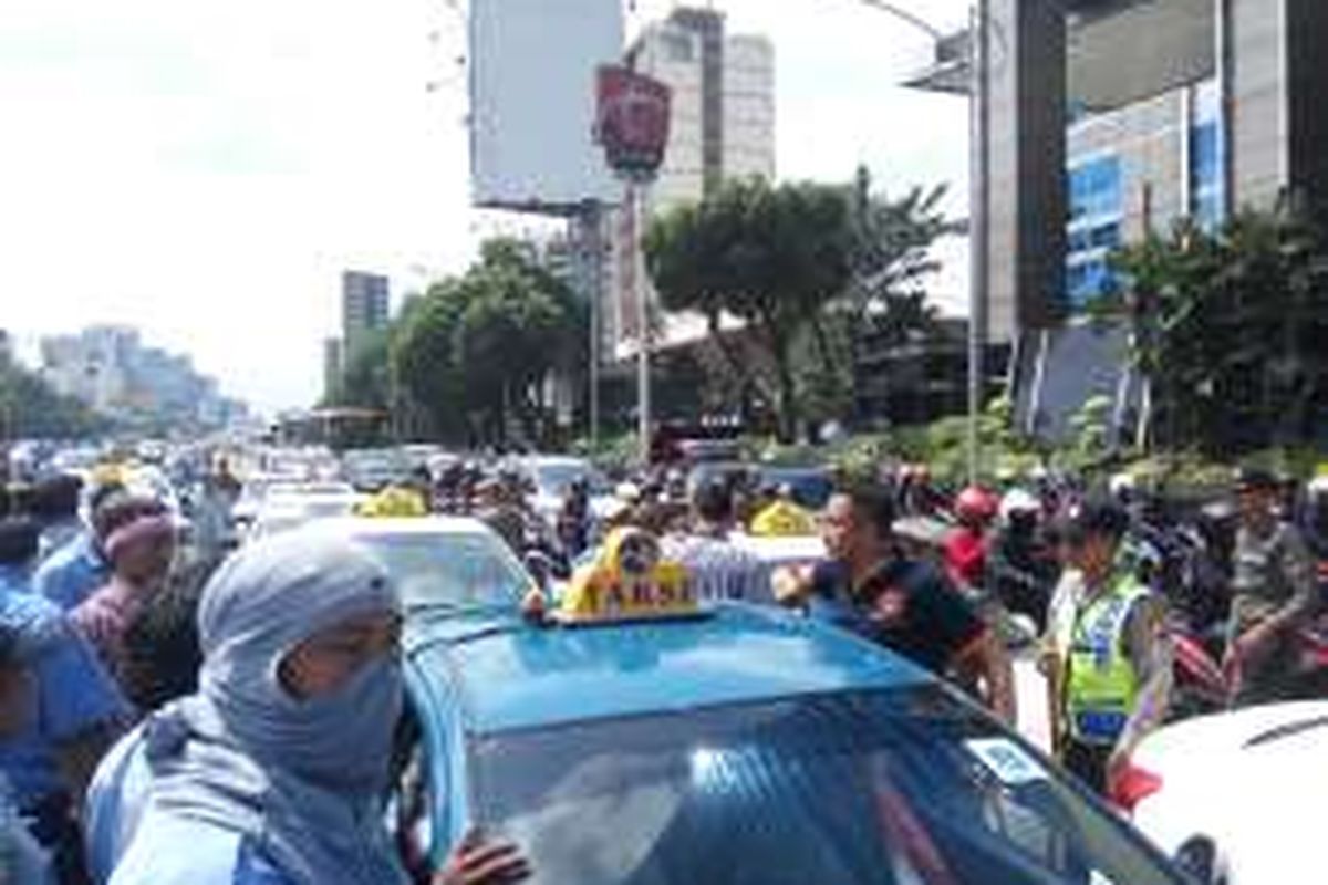 Suasana di Jalan Gatot Soebroto, Jakarta Selatan saat para supir taksi menutup sebagian ruas jalan tersebut pada Selasa (22/3/2016).