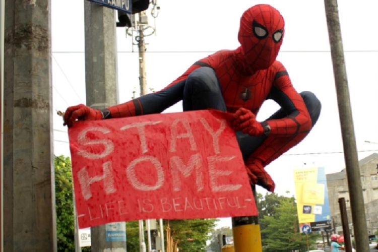 Seorang sukarelawan yang mengenakan kostum Spiderman membawa spanduk bertuliskan stay home untuk mencegah penyebaran penyakit coronavirus (COVID-19) di Makassar, Sulawesi Selatan, Indonesia, 17 April 2020. 