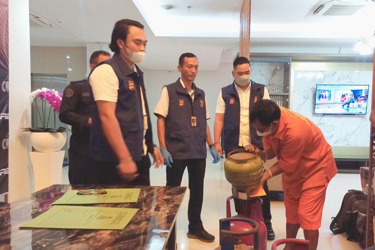 IWR (61), tersangka kasus pengoplosan elpiji saat memperagakan teknik memindahkan isi tabung gas 3 kilogram ke dalam tabung gas berukuran 12 kilogram di Gedung Ditreskrimsus Polda Bali, pada Rabu (19/6/2024). Kompas.con/ Yohanes Valdi Seriang Ginta