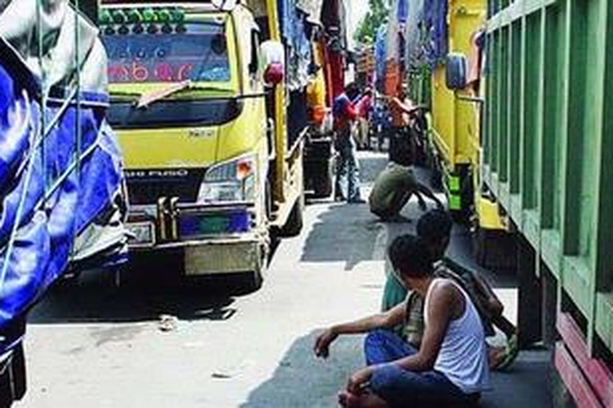 Sopir dan kernet truk yang hendak menyeberang dari Pelabuhan Merak menuju Pelabuhan Bakauheni beristirahat di sela-sela truk mereka yang terjebak kemacetan di ruas Cikuasa Atas, Kota Cilegon, Banten, Senin (21/2/2011). Ketidakpastian waktu menyeberang dan tiba di tempat tujuan pengiriman barang menghinggapi para sopir tersebut. Mereka pun harus berhemat agar uang jalan tidak habis tersedot untuk pengeluaran selama menunggu antrean terurai.