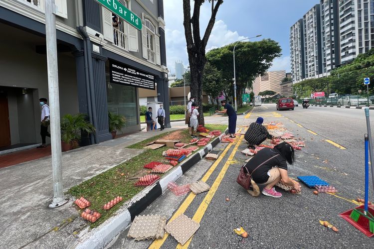 Warga Singapura coba bersihkan dan kumpulkan telur yang jatuh dari truk di kawasan Paya Lebar, Singapura, 11 Juni.