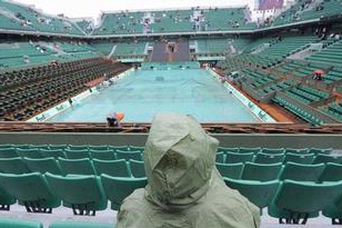 Seorang penonton menggunakan jas hujan di Roland Garros. Hujan yang mengguyur, membuat pertandingan hari kelima Grand Slam Perancis Terbuka, Kamis (27/5/10), tidak berjalan sesuai dengan jadwal.