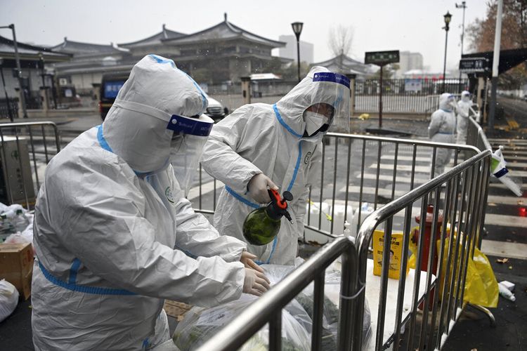Dalam foto yang dirilis oleh Kantor Berita Xinhua, pekerja yang mengenakan pakaian pelindung mendisinfeksi sayuran yang dikemas di area perumahan yang dikarantina di Xi'an di Provinsi Shaanxi, China barat laut pada 25 Desember 2021. 
