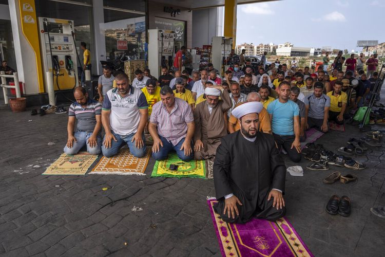 Muslim worshippers pray during Friday prayers at a gas station to protest severe fuel shortages that Lebanon has been witnessing for weeks, in the coastal town of Jiyeh, south of Beirut, Lebanon, Friday, Sept. 3, 2021.  Lebanon is mired in a devastating economic and financial crisis, the worst in its modern history. A result of this has been crippling power cuts and severe shortages in gasoline and diesel that have been blamed on smuggling, hoarding and the cash-strapped government?s inability to secure deliveries of oil products. (AP Photo/ Hassan Ammar)