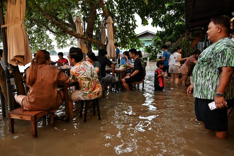 Pengunjung kafe Chaopraya Antique Cafe tampak santai menyantap hidangan meski dikelilingi bahkan direndam air banjir dari Sungai Chao Phraya, di Nonthaburi, utara Bangkok, Thailand, pada Kamis (7/10/2021).