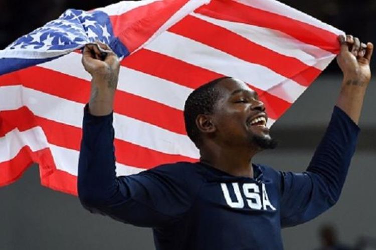 Kevin Durant mengibarkan bendera Amerika Serikat seusai timnya memenangi medali emas Olimpiade 2016 usai final versus Serbia, Minggu (21/8/2016). 