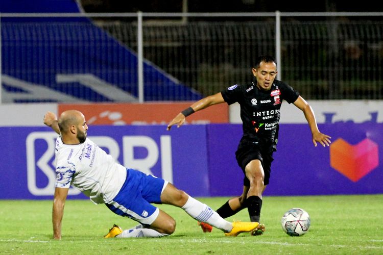 Pemain Madura United Slamet Nurcahyo (kanan) diganggu pemain asing Persib Bandung Mohammed Rashid (kiri) saat pertandingan pekan 31 Liga 1 2021-2022 yang berakhir dengan skor 3-2 di Stadion I Gusti Ngurah Rai Denpasar, Minggu (13/3/2021) malam. Terkini, laga Persib vs Madura United akan tersaji pada pekan kedua Liga 1 2022-2023.