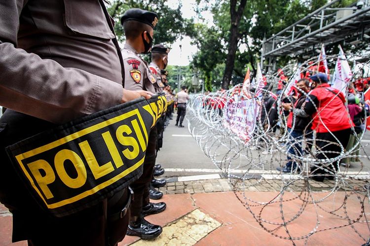 Petugas kepolisian berjaga saat massa dari KSPI berunjuk rasa di Jalan Medan Merdeka Barat, Jakarta, Senin (12/10/2020). Aksi tersebut untuk menolak disahkannya Undang-Undang Cipta Kerja.