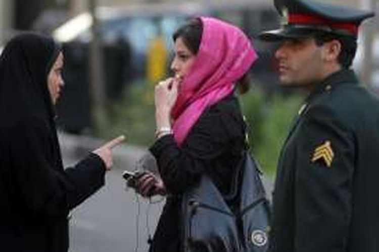 Seorang polwan Iran memperingatkan seorang perempuan yang dinilai tak mengenakan kerudung dengan tepat.